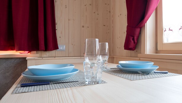 Una mesa de comedor con platos azules, vasos transparentes y un sujetavasos azul.