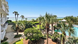 A resort with a pool, palm trees, and a view of the ocean. - The Crescent 207 (Destin)