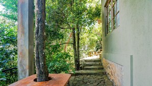 A narrow stone staircase leading up to a building with a wooden bench and a tree in the foreground.