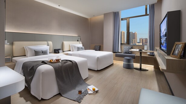 A modern hotel room with two beds, a desk, a TV, and a large window with a city view. - SPEY HOTEL (Guangzhou)