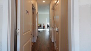 A hallway with closed doors, a dining area in the background, and a ceiling light. - New house in Redmond, 15 minutes to Airport and Smith Rock (Redmond)