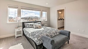 A bedroom with a large bed, a nightstand, a chair, and a view of the outside. - New house in Redmond, 15 minutes to Airport and Smith Rock (Redmond)