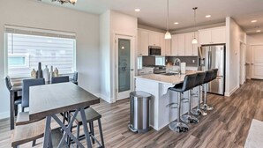 A modern kitchen with white cabinets, stainless steel appliances, and a central island with bar stools. - New house in Redmond, 15 minutes to Airport and Smith Rock (Redmond)