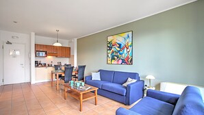 Een woonkamer met een blauwe bank, een salontafel en een schilderij aan de muur.