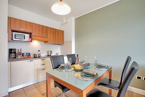 A modern kitchen with wooden cabinets, a microwave, and a dining table set for four with chairs.