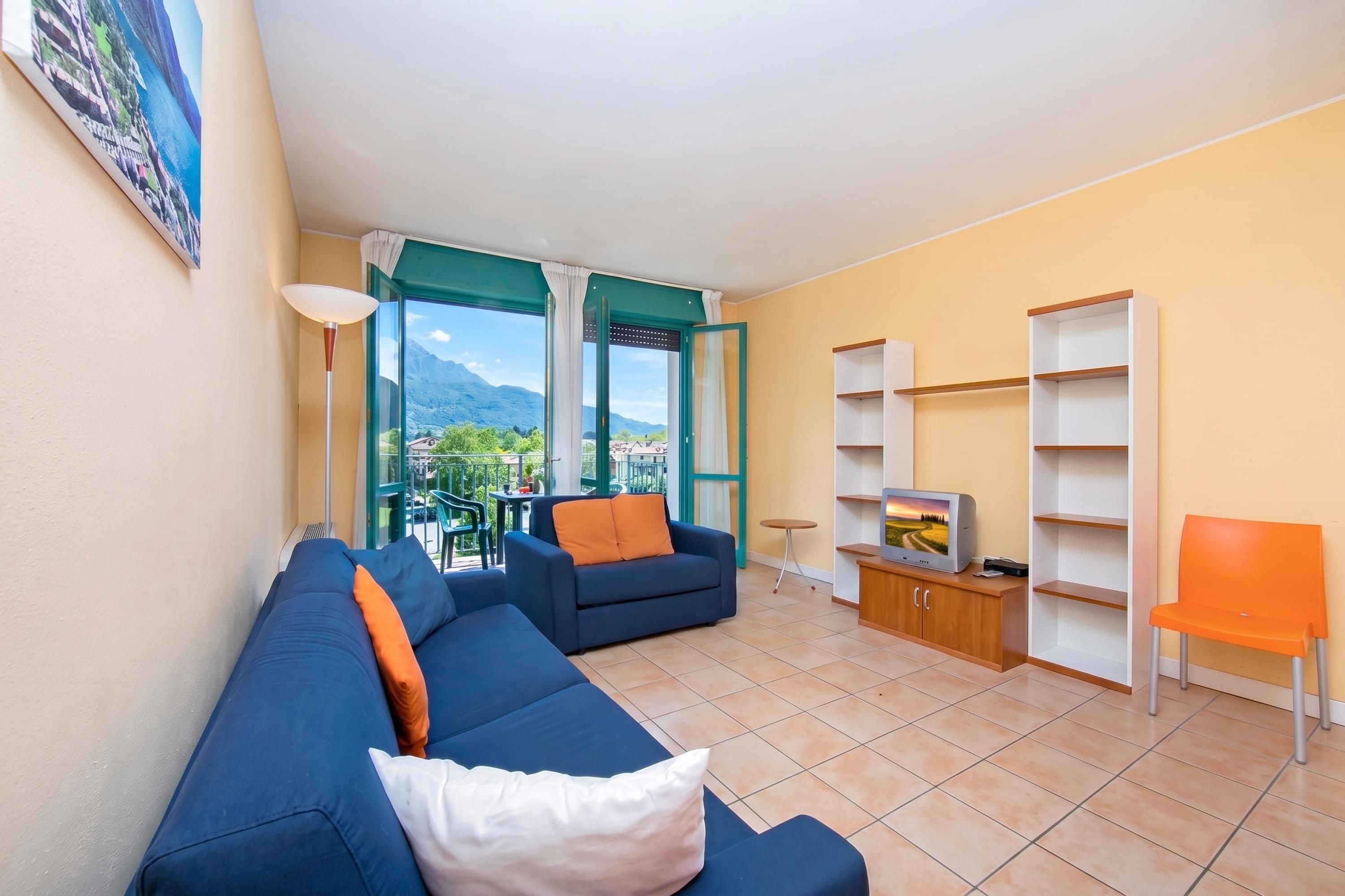A living room with a sofa, a TV stand, and a view of mountains through a glass door.