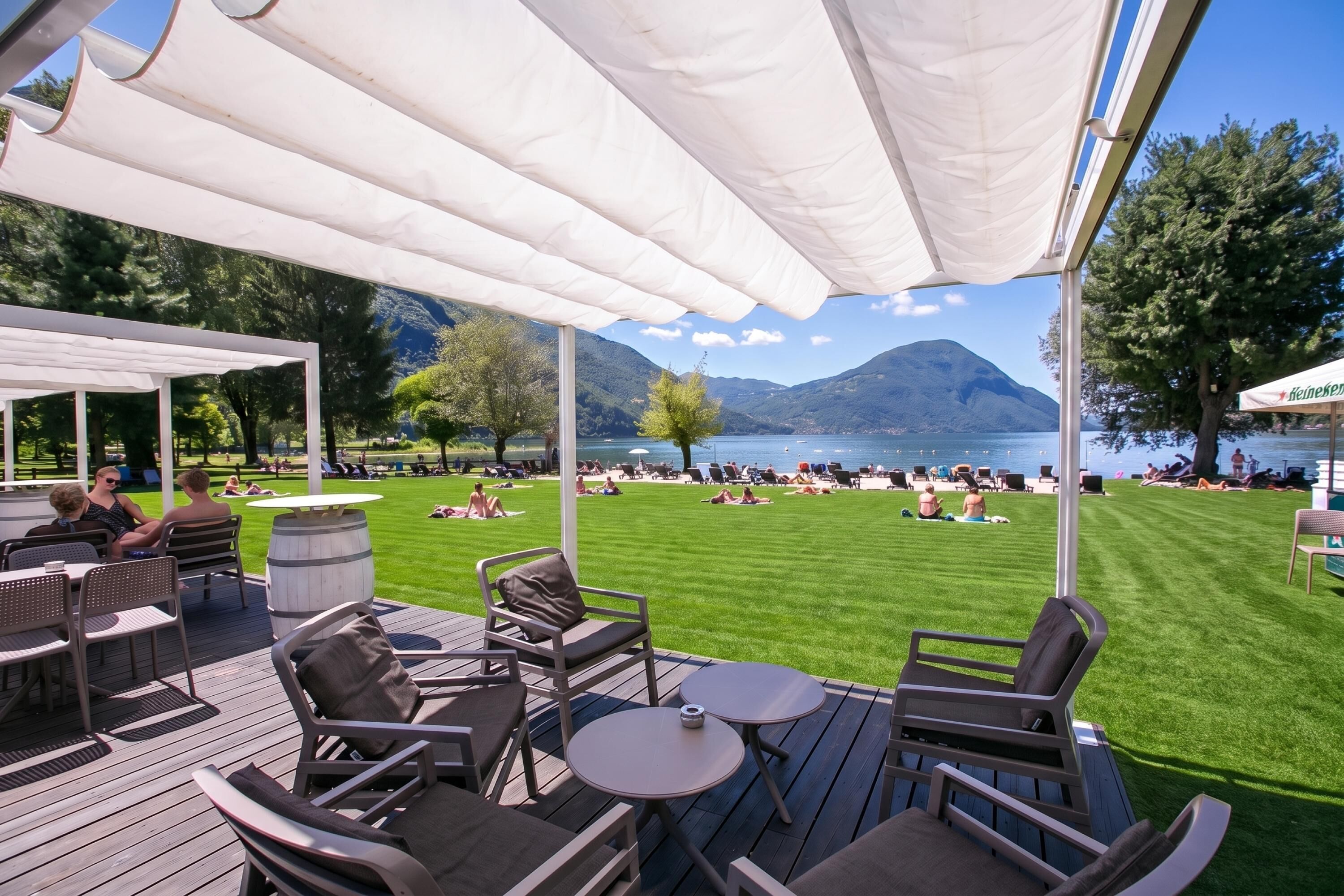 An outdoor seating area with tables and chairs, overlooking a lake and mountains.