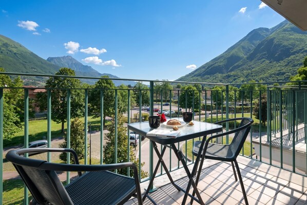 A balcony with a table and chairs, overlooking a mountainous landscape.