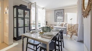Un coin repas avec une table dressée pour quatre personnes, un meuble noir et un canapé à l’arrière-plan.