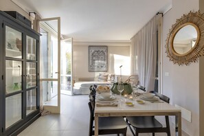 Een eetruimte met een tafel voor vier personen, een kast met glazen deuren, een lijstwerk aan de muur en een grote spiegel.