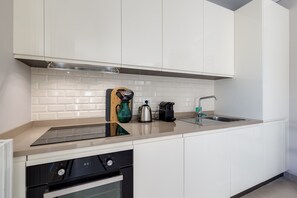 A modern kitchen with white cabinets, a stainless steel sink, and a built-in oven.