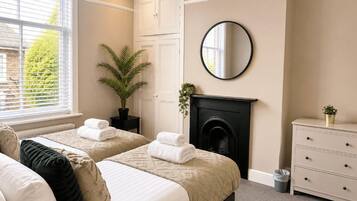 Quarto com duas camas, lareira, espelho e penteadeira.