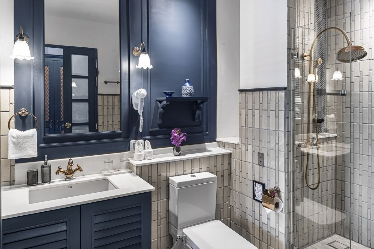 A bathroom with a large mirror, a sink, a toilet, and a shower area.