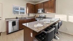 Una cocina moderna con encimeras de granito, electrodomésticos de acero inoxidable y armarios de madera.