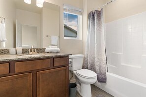 A bathroom with a granite countertop, a white toilet, a shower curtain, and a window above the toilet. - Hot Tub*A/C*Mount Elden View* (Flagstaff)