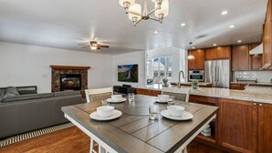 A modern kitchen with wooden cabinets, a dining area with a table set for four, and a living area with a sofa and fireplace. - White Peak Lodge *Ping-Pong*Pool-Table*PACMAN* (Flagstaff)