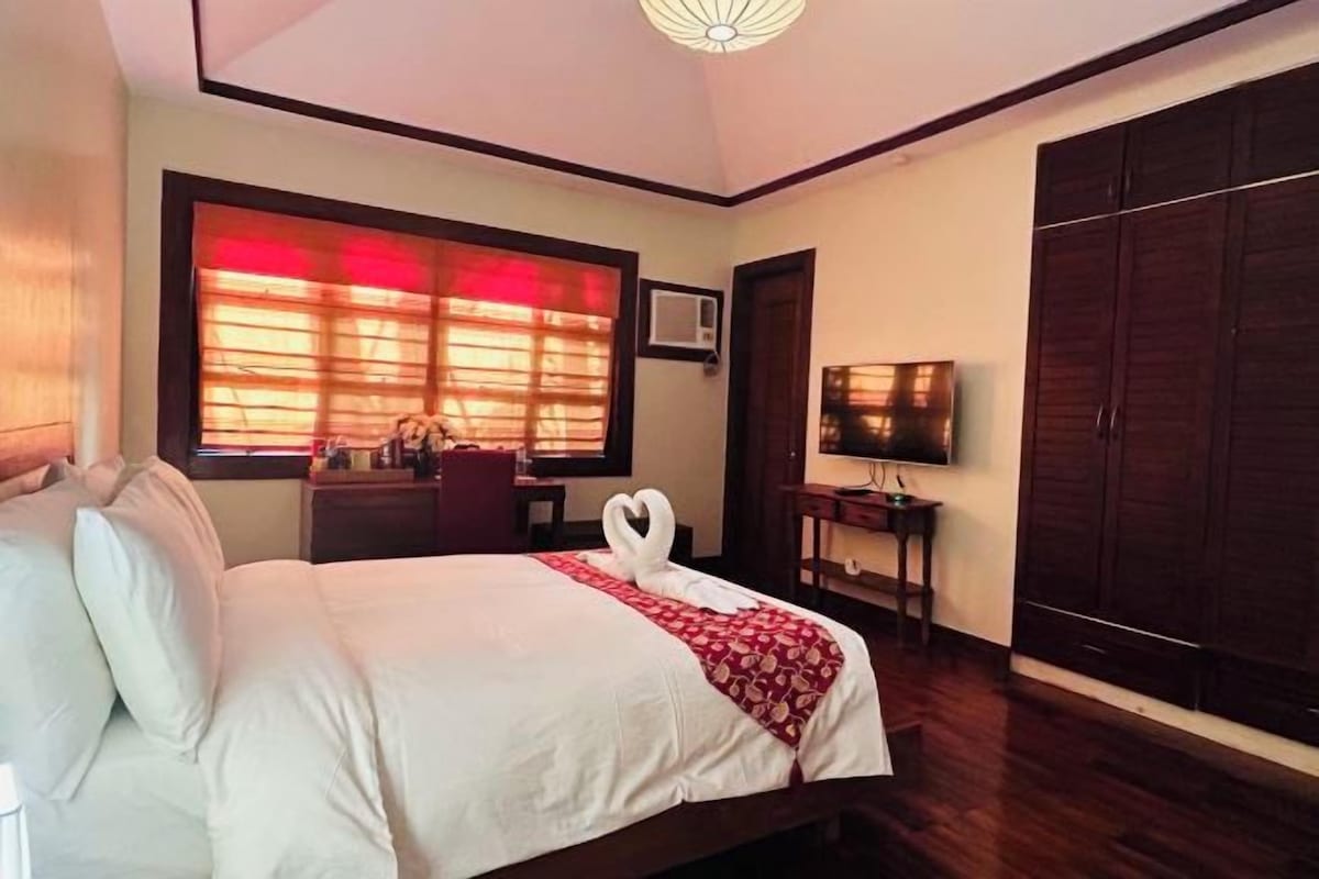 Una habitación de hotel con una cama grande, un escritorio, un televisor y un armario.