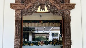 An ornate wooden entrance with intricate carvings, a tiled floor, and a decorative garland.