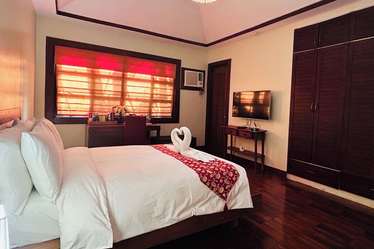 Habitación de hotel con cama, escritorio, televisor y armario.