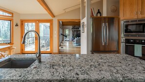 A modern kitchen with a granite countertop, stainless steel appliances, and wooden cabinets.