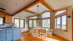 A spacious kitchen with wooden beams, large windows, and a central island with seating.