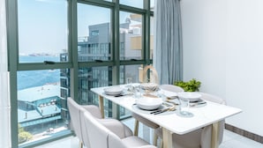 A modern dining area with a large window, a table set for four, and a view of a cityscape and water. - Marukab Plaza (Malé)