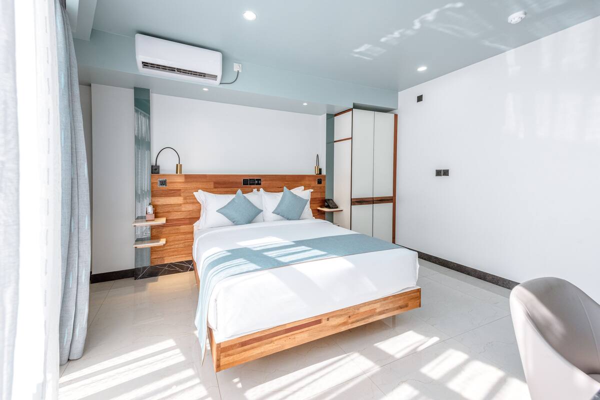 Une chambre à coucher moderne avec un cadre de lit en bois, une table de chevet, une commode et une armoire.