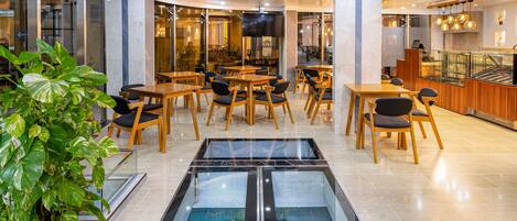 Eine moderne Hotelhalle mit einem zentralen Aquarium, Holztischen und -stühlen.