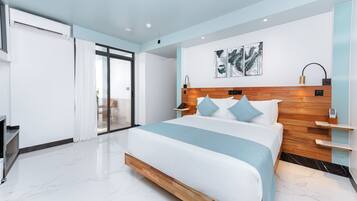 Una habitación de hotel moderna con una cama grande, cabecera de madera, puerta de vidrio que da a un balcón y una obra de arte colgada en la pared.