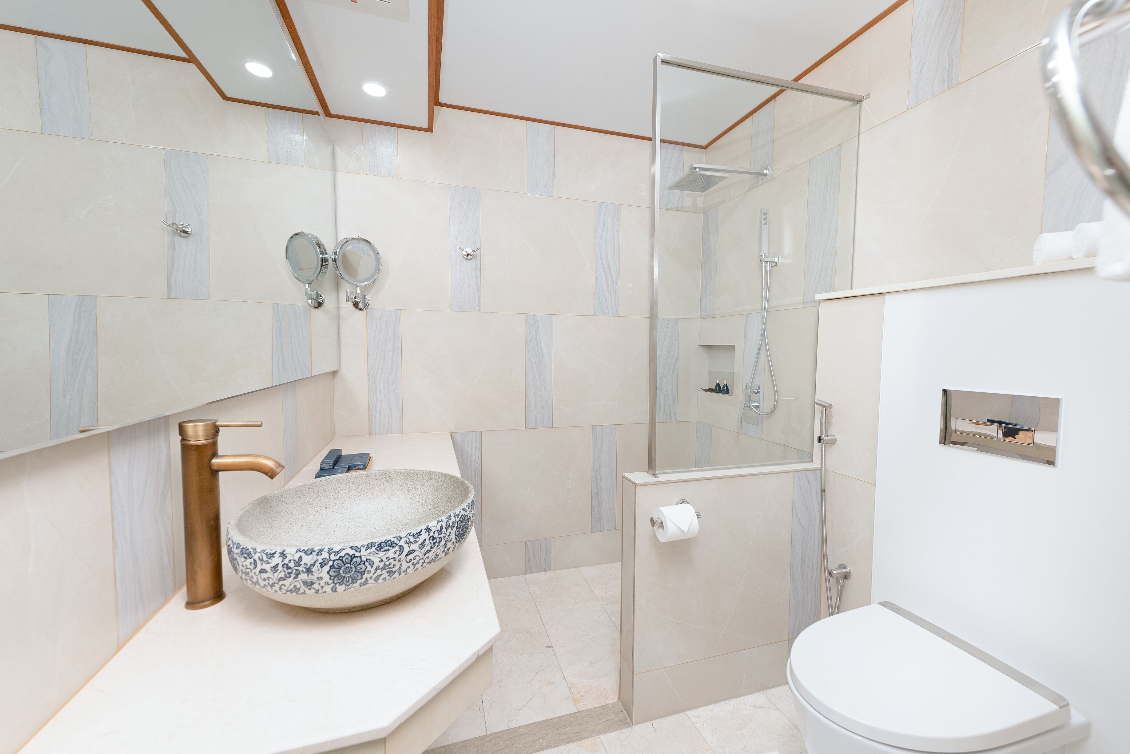 A modern bathroom with a large vessel sink, a handheld showerhead, and a toilet.
