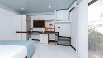 Una habitación de hotel moderna con cama, escritorio, silla y una pequeña kitchenette.