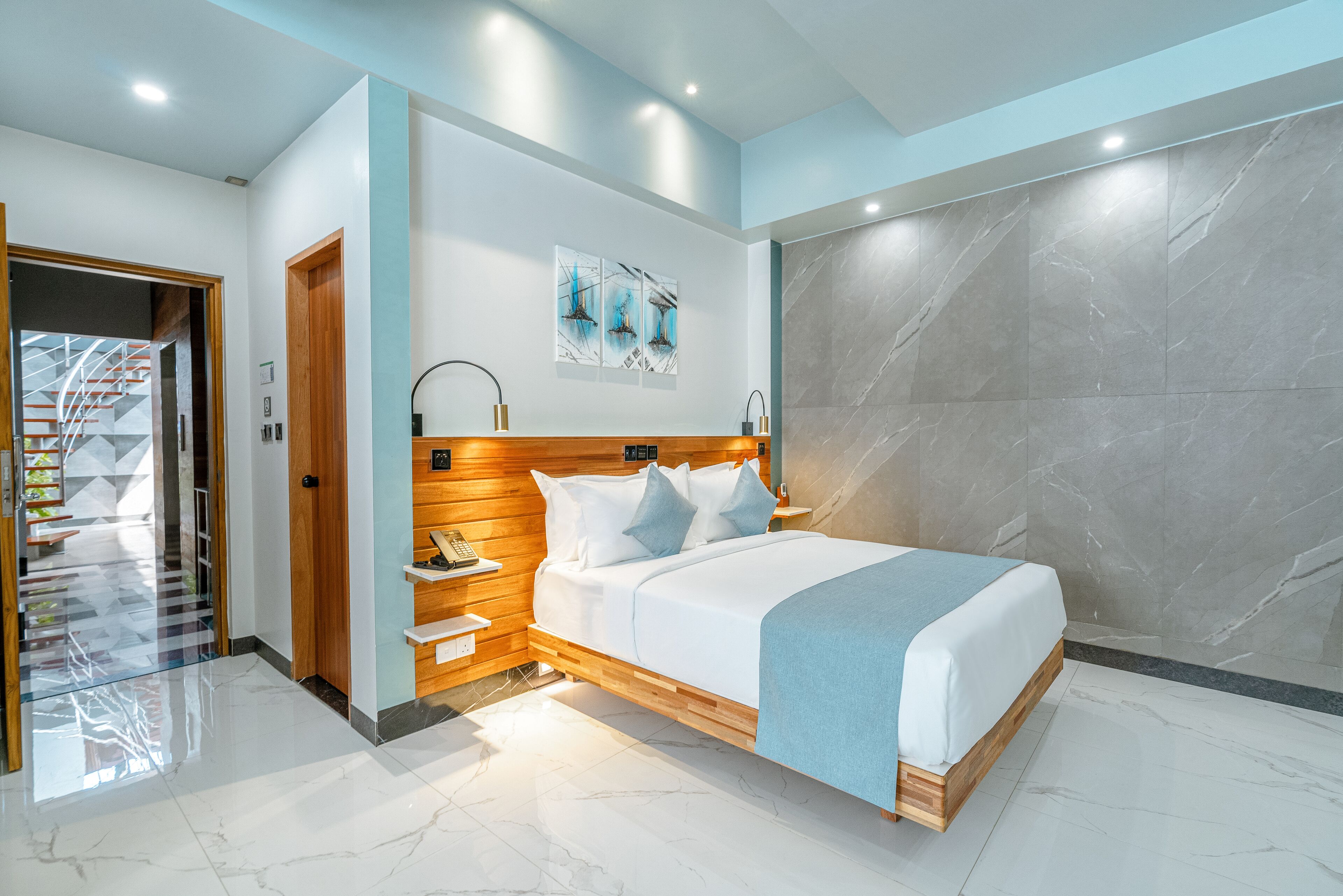 A modern bedroom with a bed, wooden headboard, bedside tables, and a marble wall.