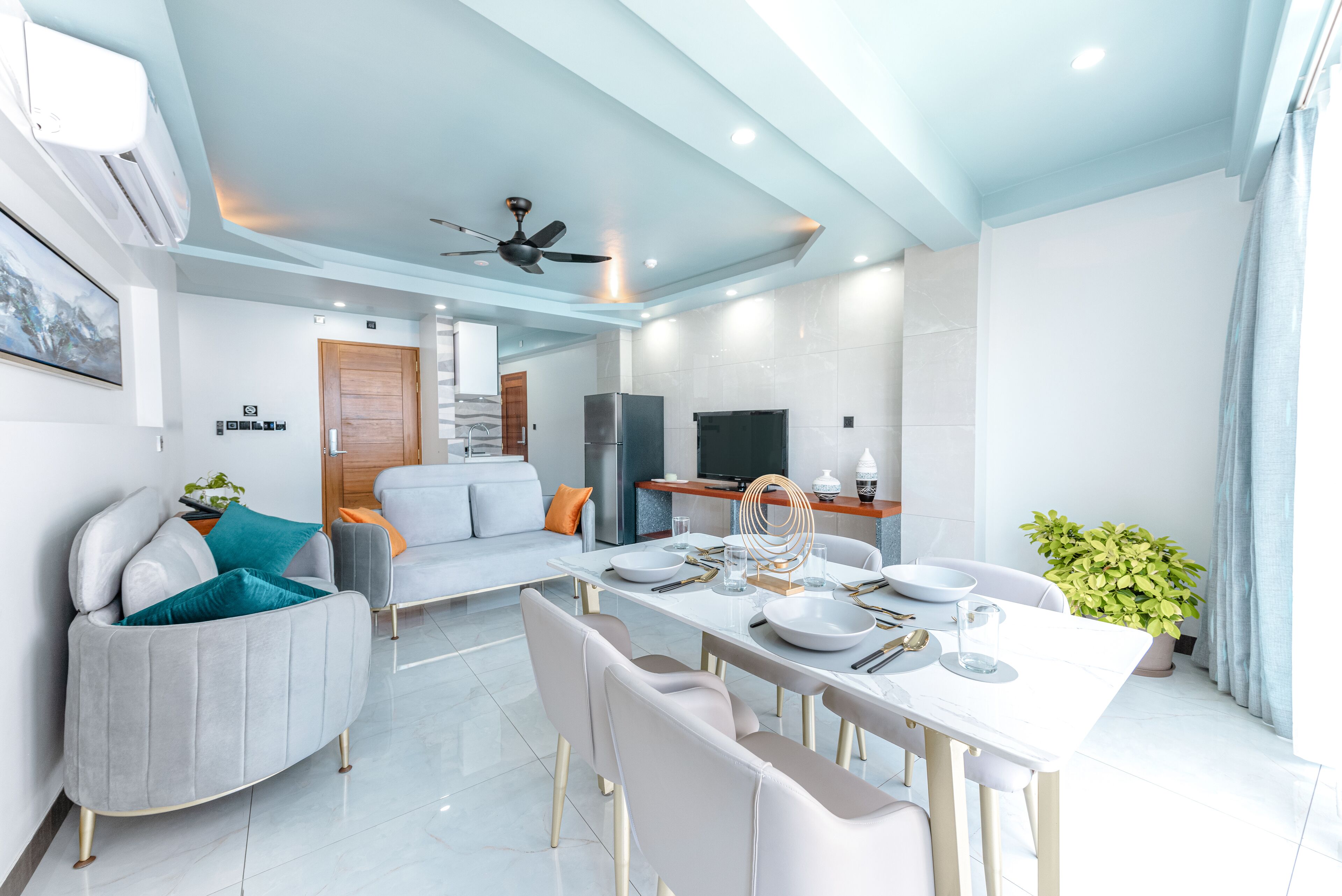 A modern living room with a dining area, featuring a sofa, a dining table set, and a ceiling fan.