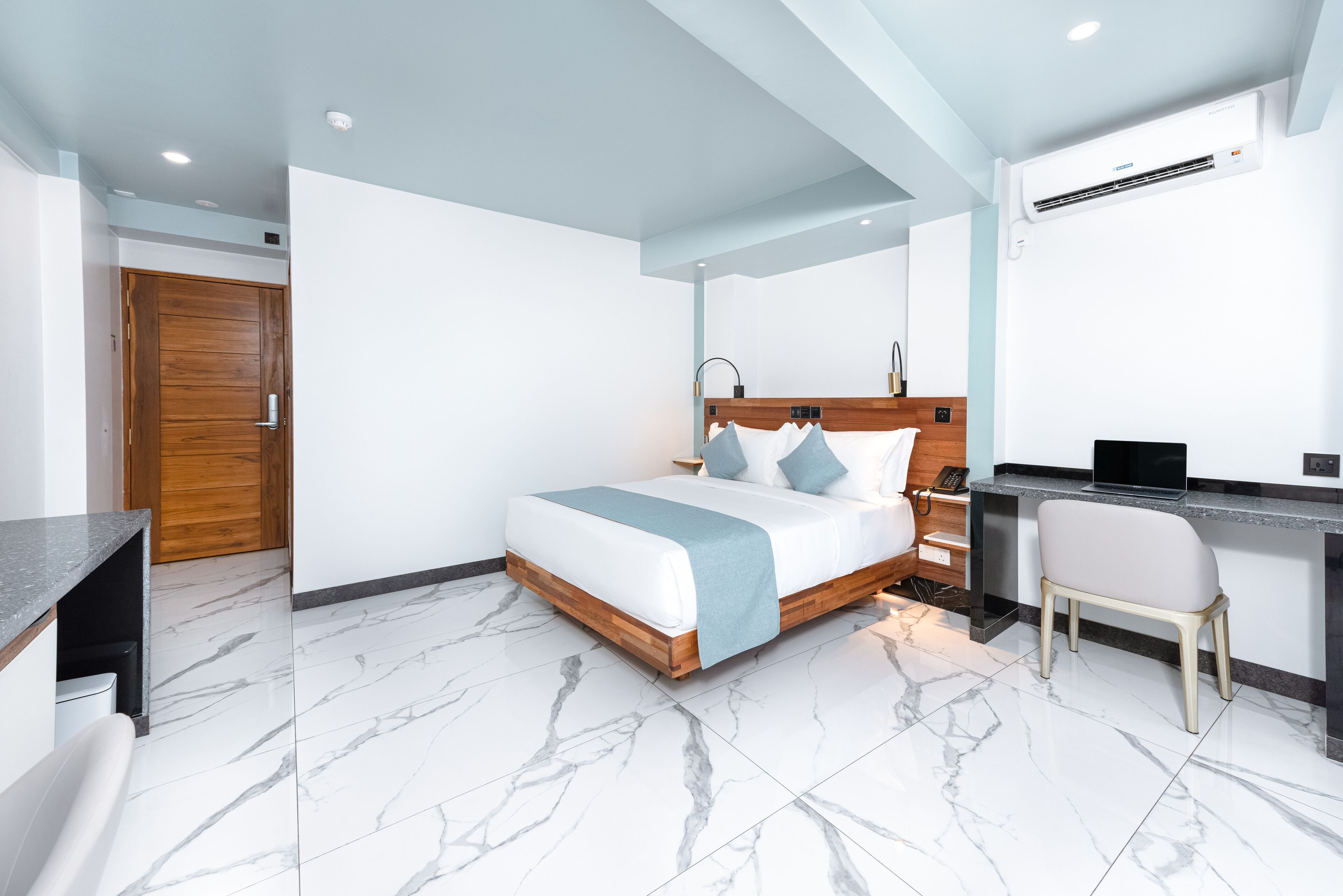 Une chambre moderne comprenant un lit, une table de chevet, une chaise et un bureau avec un ordinateur.