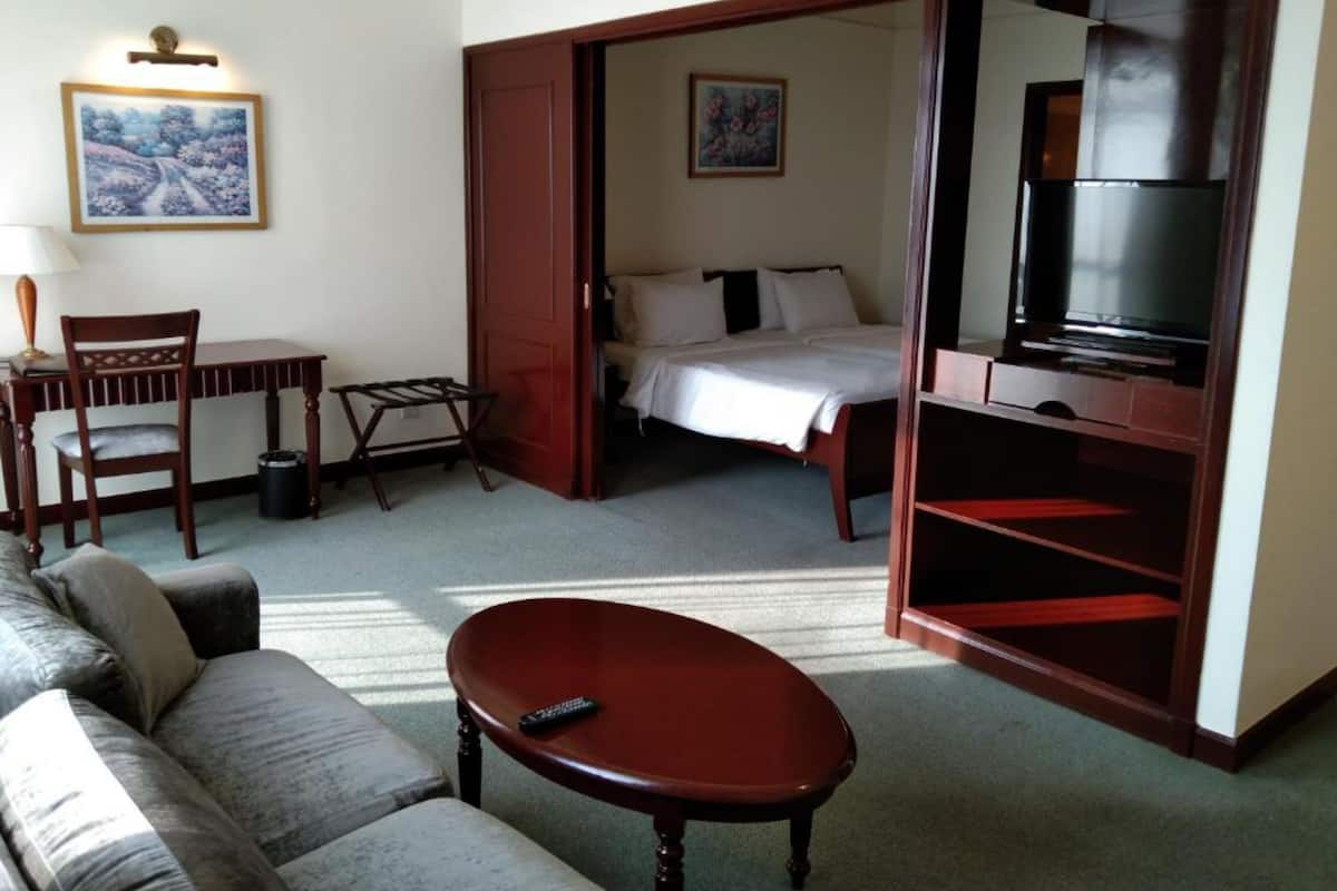 A hotel room with a bed, a TV, a sofa, a desk, and a chair.