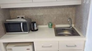 A compact kitchen with a microwave, kettle, and sink. - KL TIMES SQUARE SERVICE RESIDENCIES  (Kuala Lumpur)
