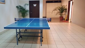 A ping pong table in a hallway with tiled flooring, potted plants, and a door in the background. - KL TIMES SQUARE SERVICE RESIDENCIES  (Kuala Lumpur)