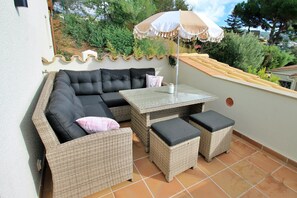 An outdoor patio with wicker furniture, including a sofa, a table, and two ottomans.