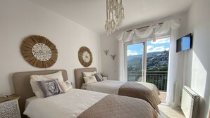 A bedroom with two beds, a large window with a view, a TV, and decorative wall art.
