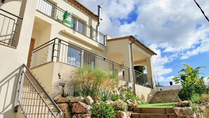 A multi-story building with balconies, a staircase, and a garden area with rocks and plants.
