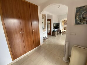 A spacious living area with a wooden wardrobe, a television, and a radiator.