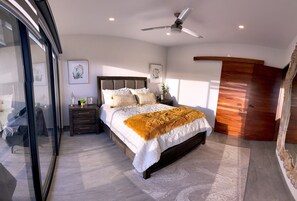 Un dormitorio moderno con una cama grande, un ventilador de techo y un armario de madera.