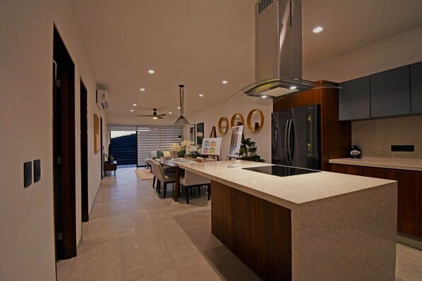 Una cocina moderna con una isla central, electrodomésticos integrados y un comedor con vistas.