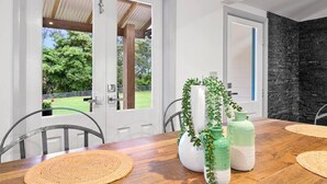 A dining area with a wooden table, woven placemats, and green decorative vases.