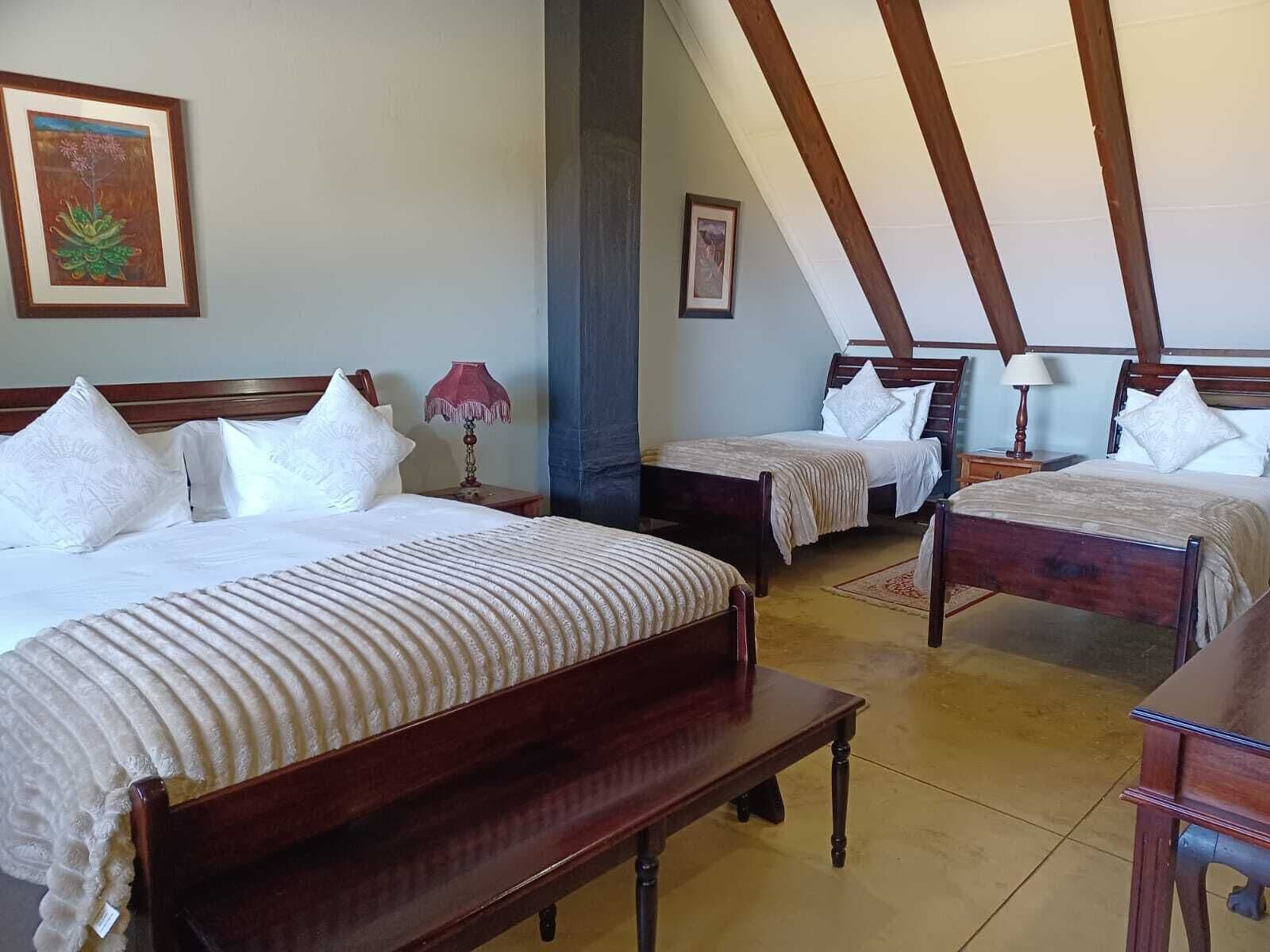 Habitación de hotel con dos camas, un banco y una mesa de madera.