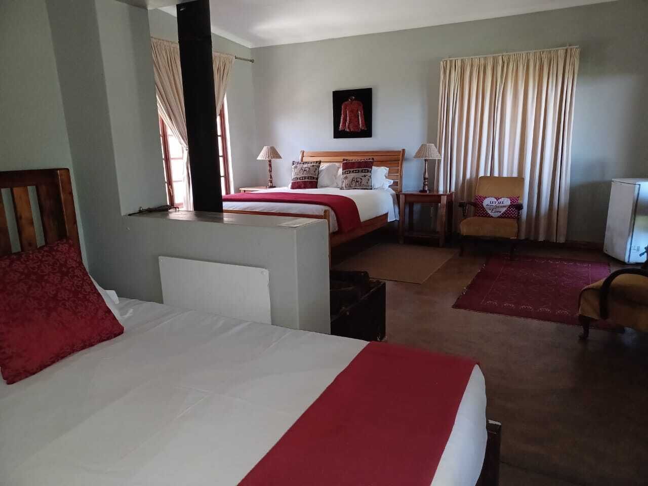 A hotel room with two beds, a chair, a desk, and a TV.
