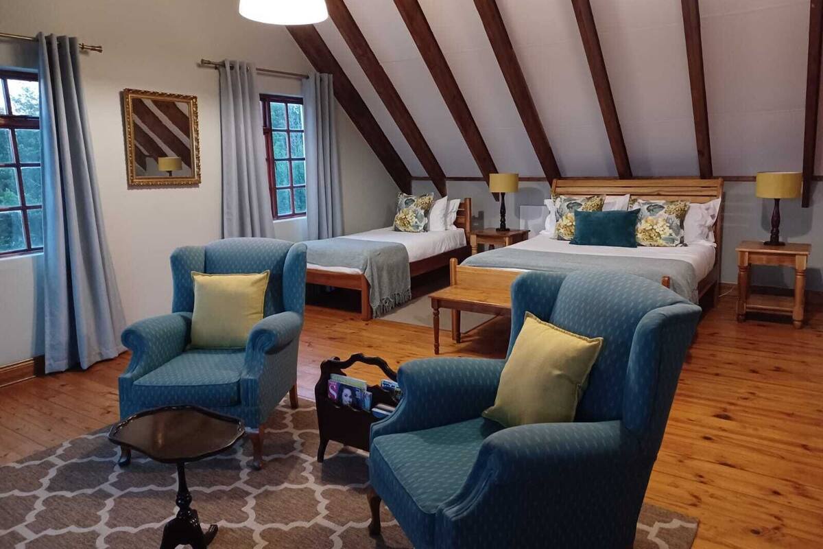 A cozy room with two beds, a wooden ceiling, and a window with curtains.