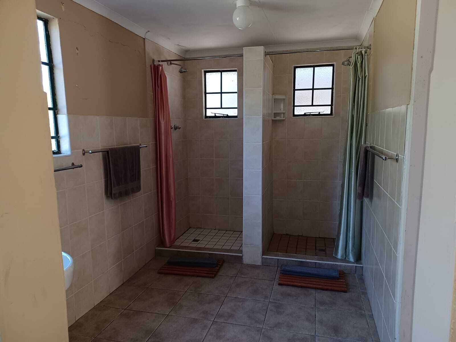 A small, tiled bathroom with a shower area, a window, and a towel rack.