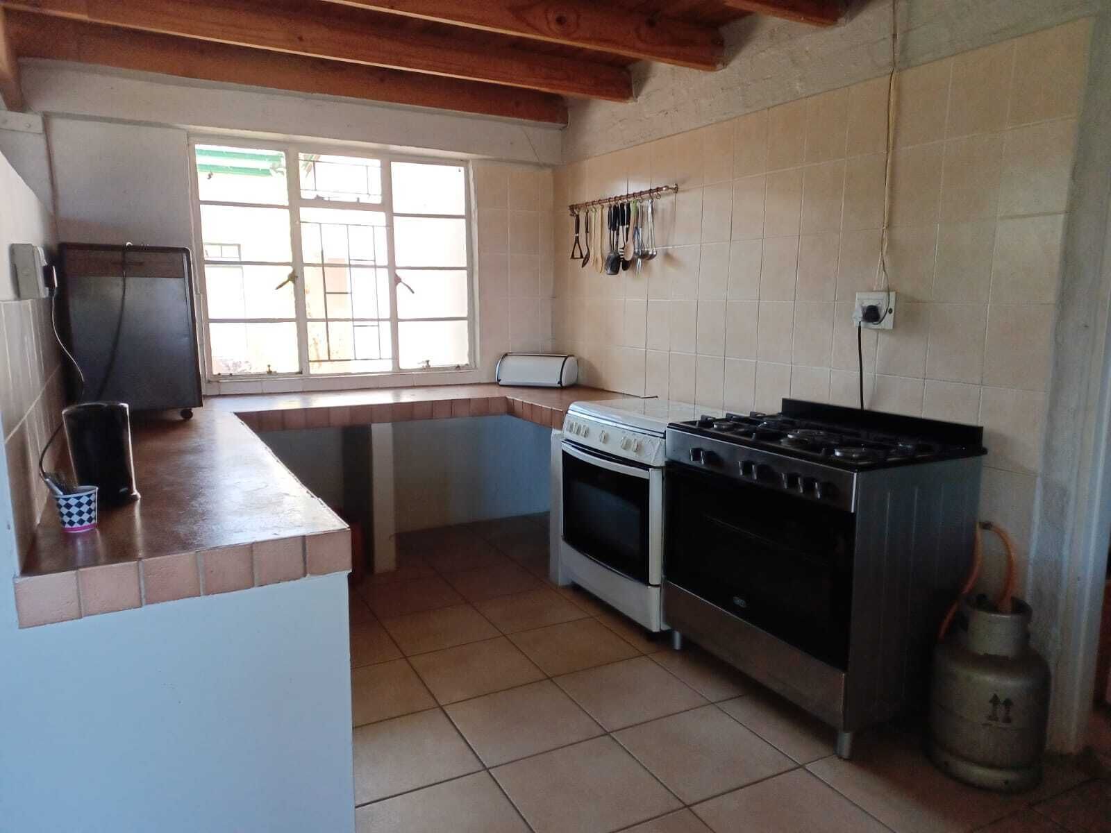 A compact kitchen with a gas stove, oven, and a small refrigerator.