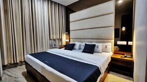 A hotel room with a large bed, a bedside table with a phone, and a wall-mounted light. - Hotel 21 Chandigarh (Chandigarh)